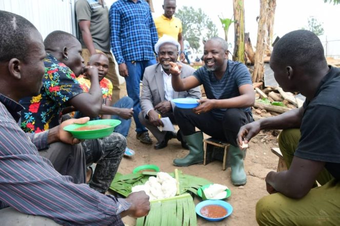 Tayebwa-in-green-boots-with-residents-enjoying-a-meal